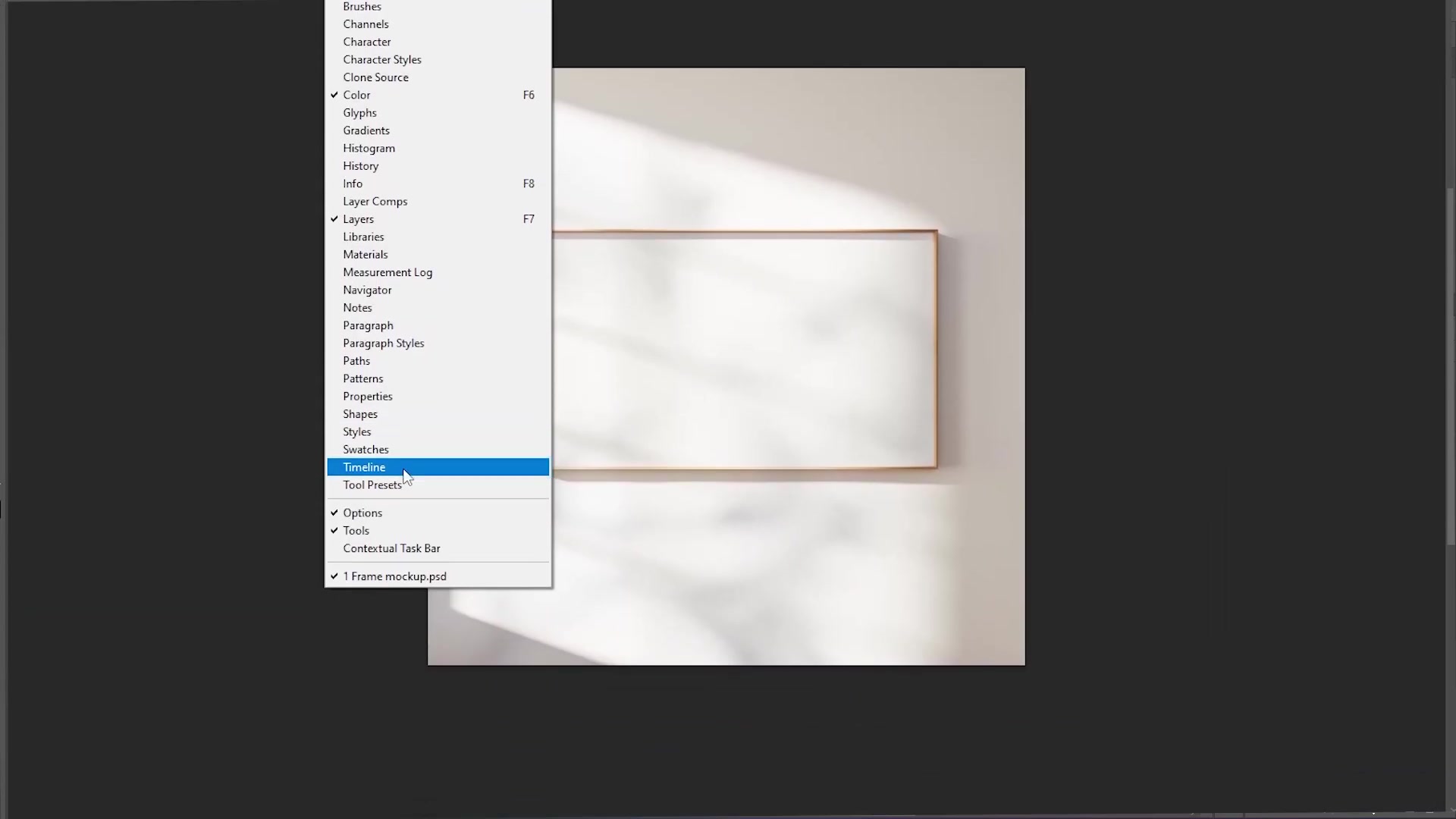 Adobe Photoshop interface with Timeline panel open at the bottom, displaying video layers and playback controls below the 'Frame mockup.psd' canvas of a blank frame on a wall.